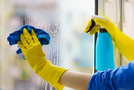 Sud's Spotless technician hand-cleaning a window with a spray bottle and cloth